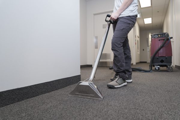 woman removing dirt from carpet with professional vacuum cleaner